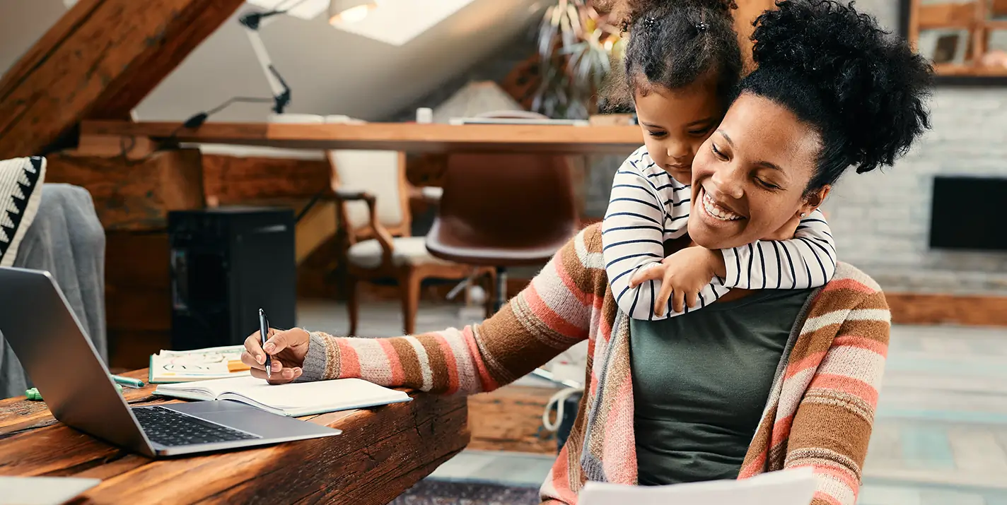 A woman and a child smiling and looking at a laptop